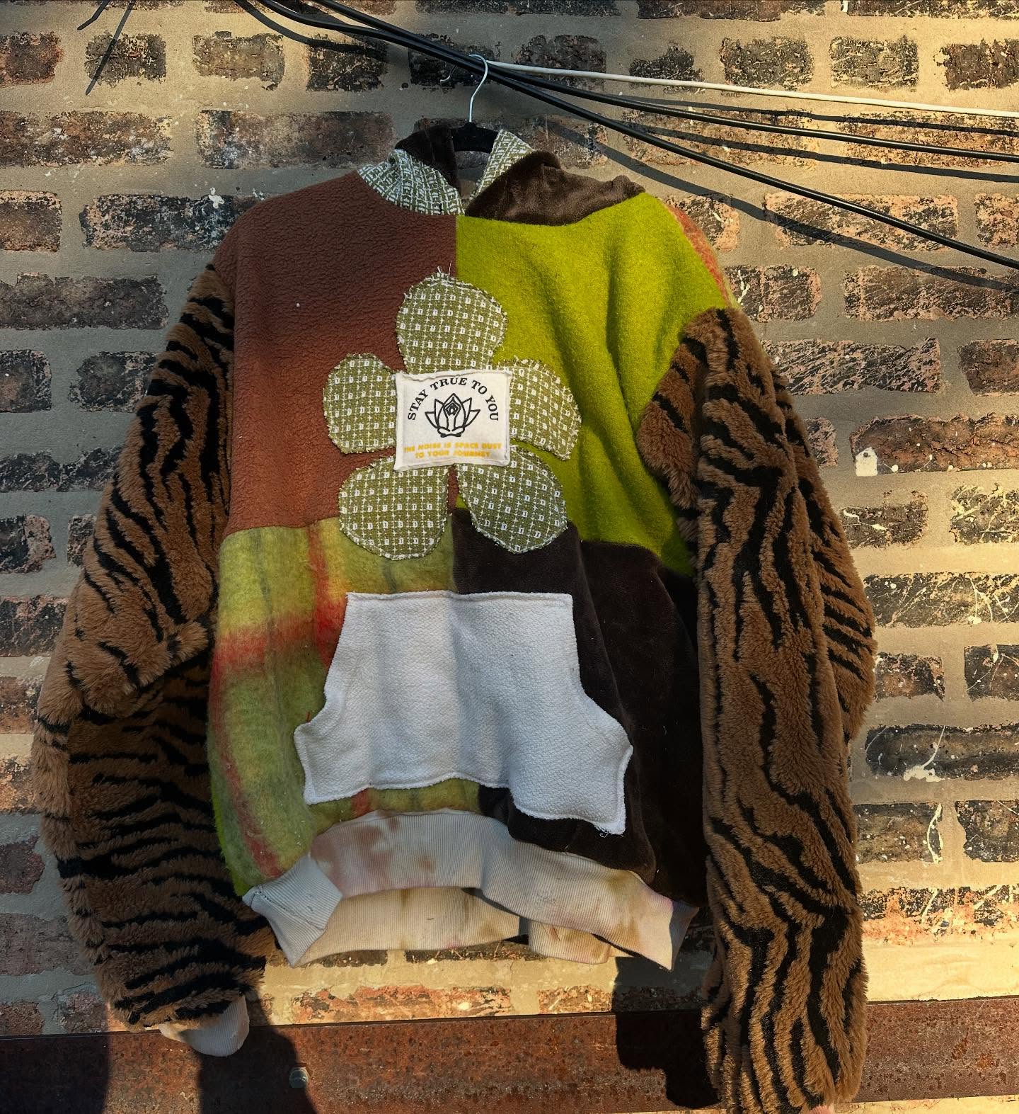 Colorblocked blanket hoodie with tiger fleece sleeves and a Stay True to You flower patch