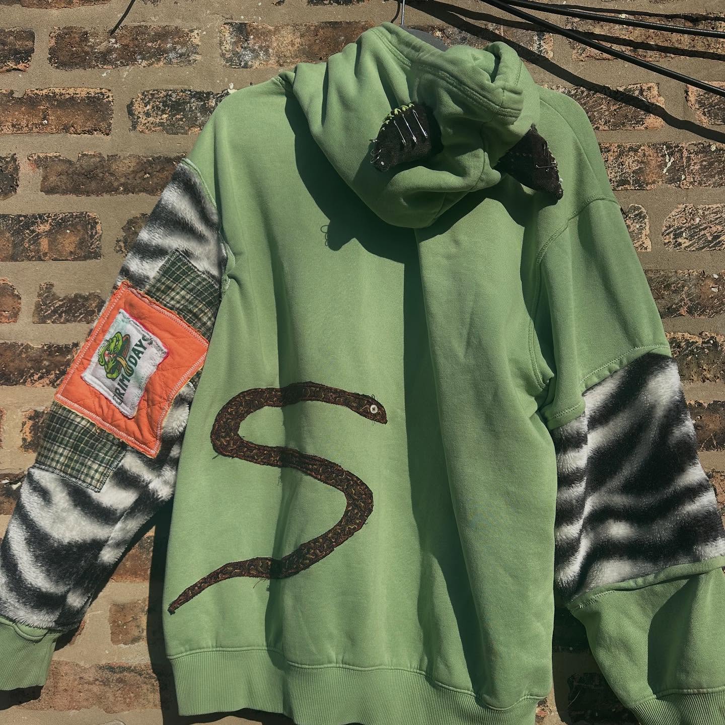 Green horn hoodie with zebra sleeves against brick